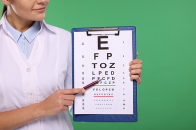 Ophthalmologist pointing at vision test chart on green background, closeup