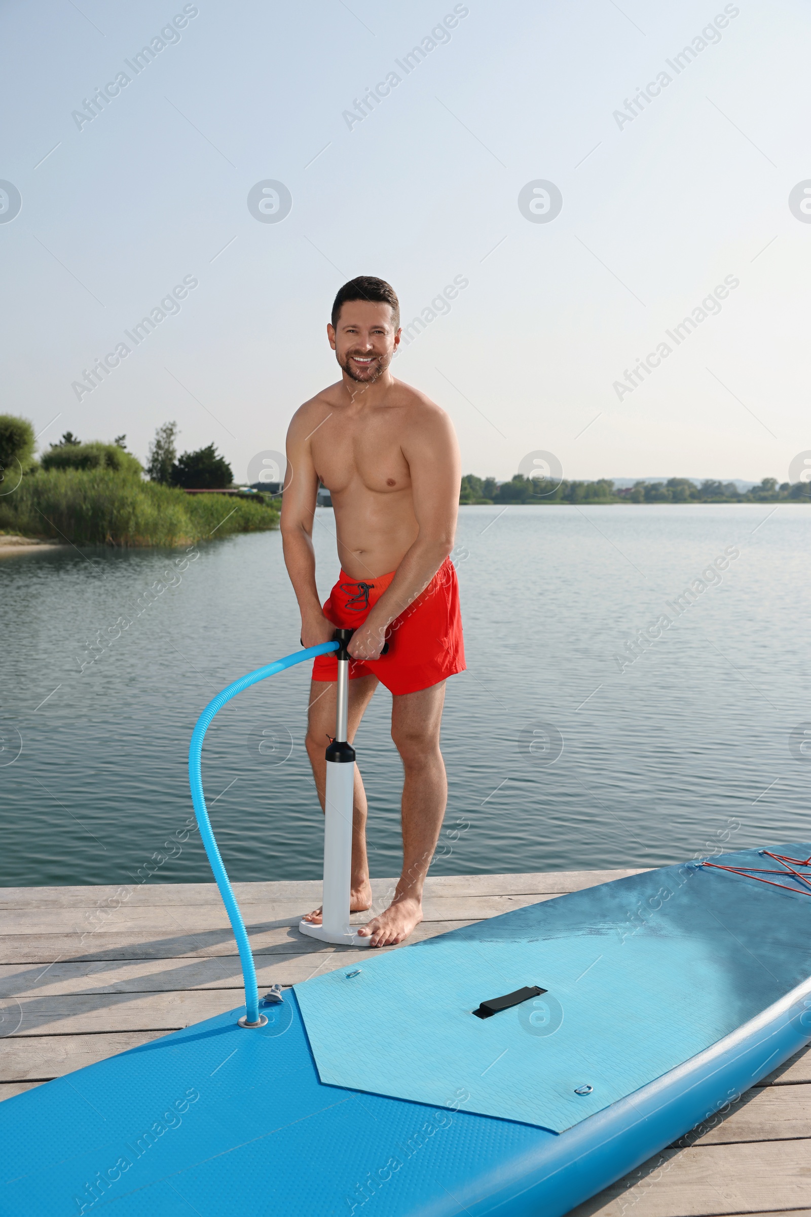 Photo of Man pumping up SUP board on pier