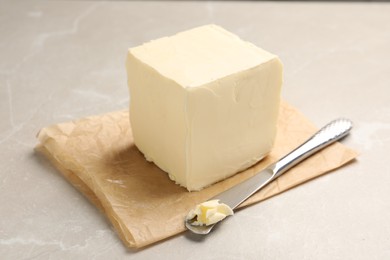 Block of tasty butter and knife on light table