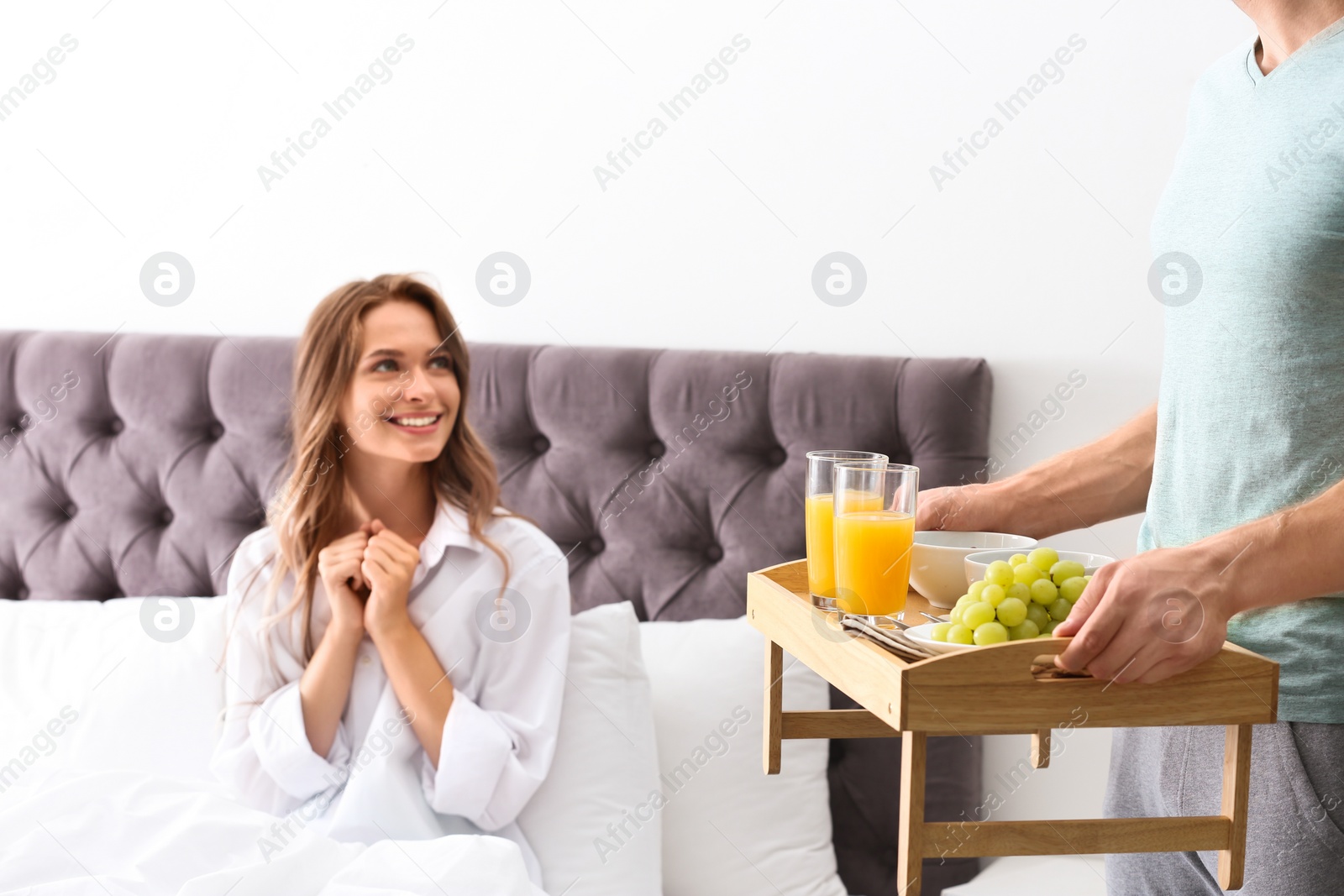 Photo of Young man bringing romantic breakfast to his girlfriend in bed at home