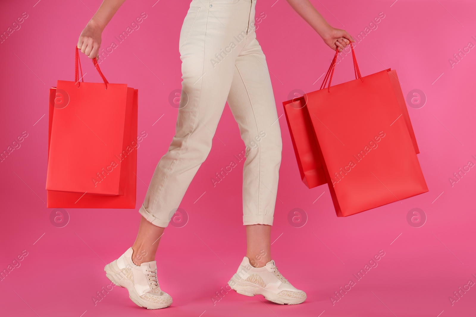 Photo of Woman with shopping bags on pink background, closeup. Black Friday Sale