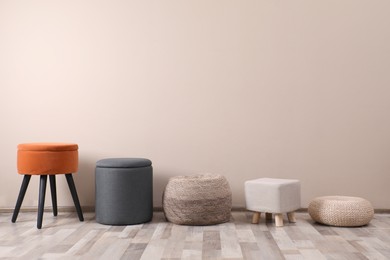 Photo of Different stylish poufs and ottomans near beige wall, space for text