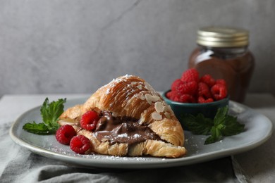 Delicious croissant with chocolate and raspberries on table
