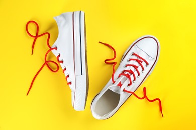 Photo of Pairtrendy sneakers on yellow background, flat lay