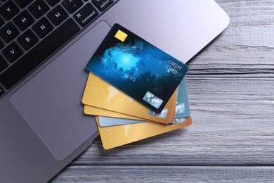 Photo of Credit cards and laptop on grey wooden table, flat lay