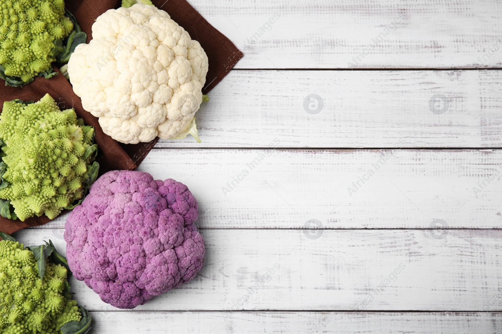 Photo of Different fresh cabbages on white wooden table, flat lay. Space for text