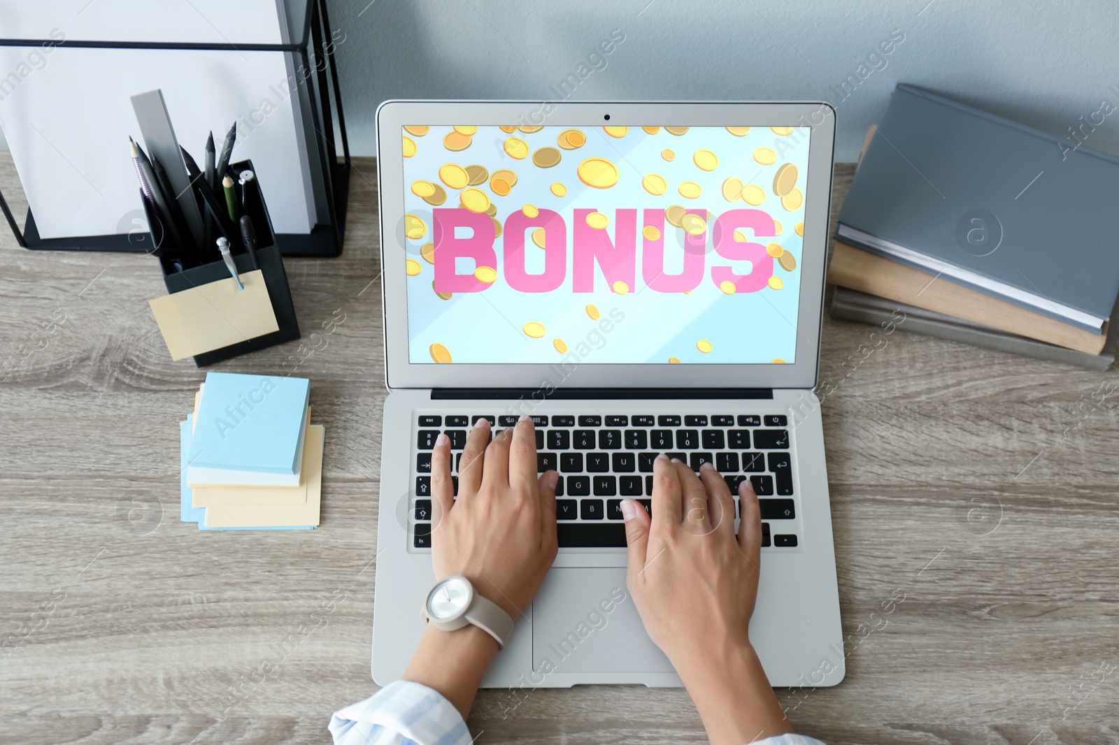 Image of Bonus gaining. Woman using laptop at wooden table, above view. Illustration of falling coins and word on device screen