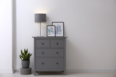 Photo of Grey chest of drawers in stylish room interior. Space for text