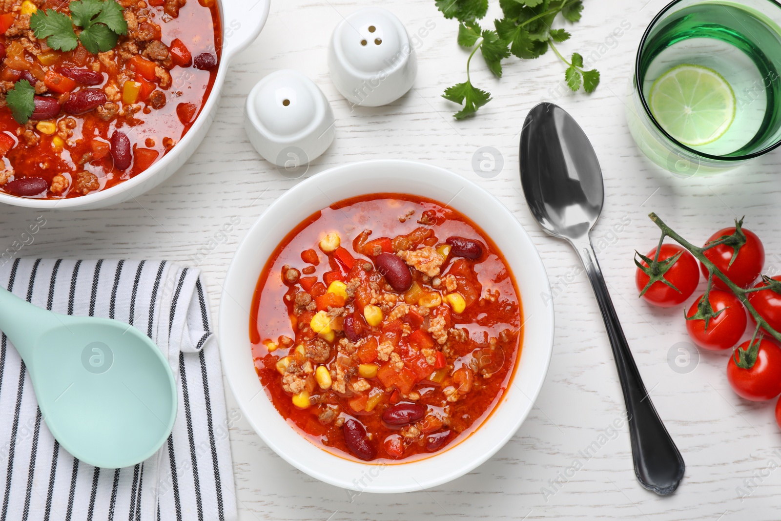 Photo of Tasty chili con carne served on white wooden table, flat lay