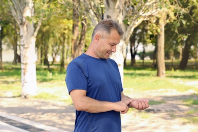 Photo of Man checking pulse outdoors on sunny day