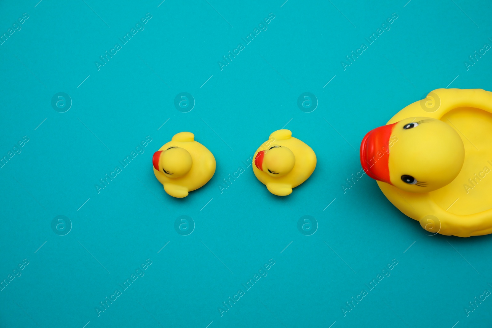 Photo of Rubber toy ducks on teal background, flat lay