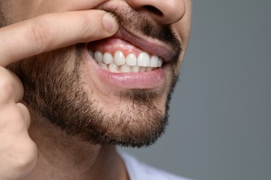 Man showing healthy gums on gray background, closeup. Space for text