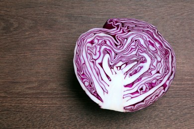 Photo of Half of fresh red cabbage on wooden table, top view. Space for text