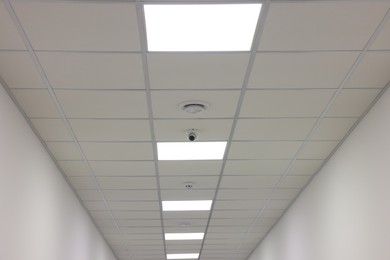 Photo of White ceiling with PVC tiles and lighting indoors, low angle view