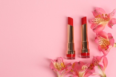 Bright lipsticks and spring flowers on pink background, flat lay. Space for text