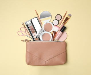 Cosmetic bag with makeup products and beauty accessories on beige background, flat lay
