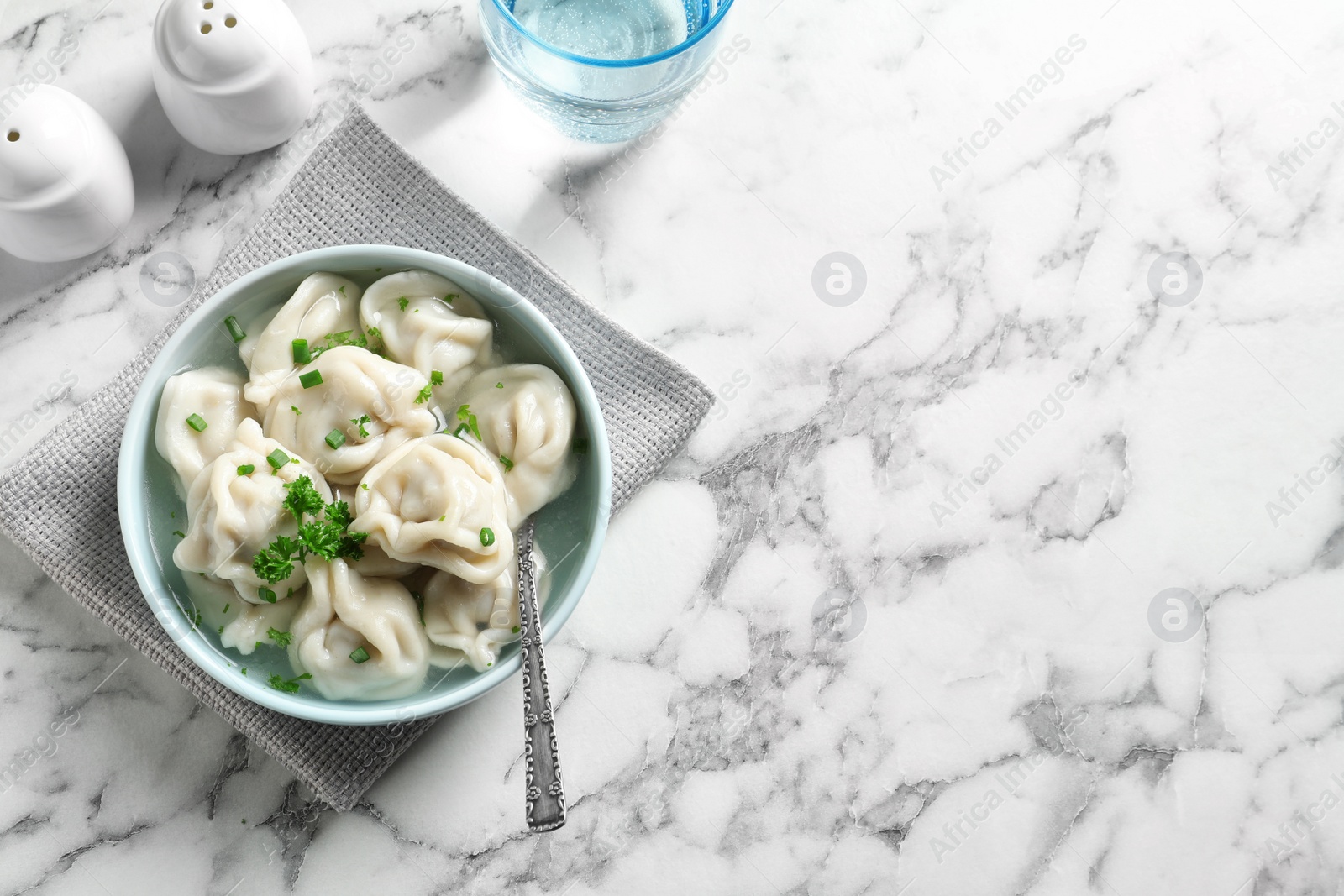 Photo of Bowl of tasty dumplings served on white marble table, top view. Space for text