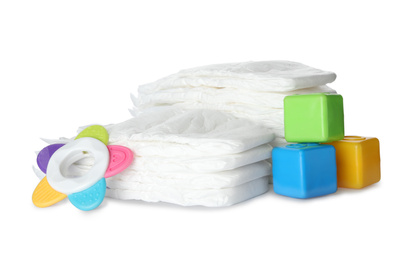 Disposable diapers, colorful cubes and teether on white background
