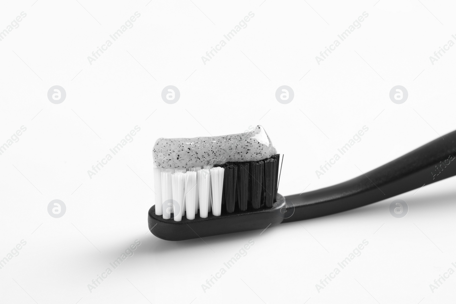 Photo of Brush with charcoal toothpaste on white background