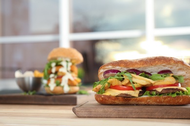 Photo of Wooden serving plate with yummy sandwich on table in cafe. Space for text