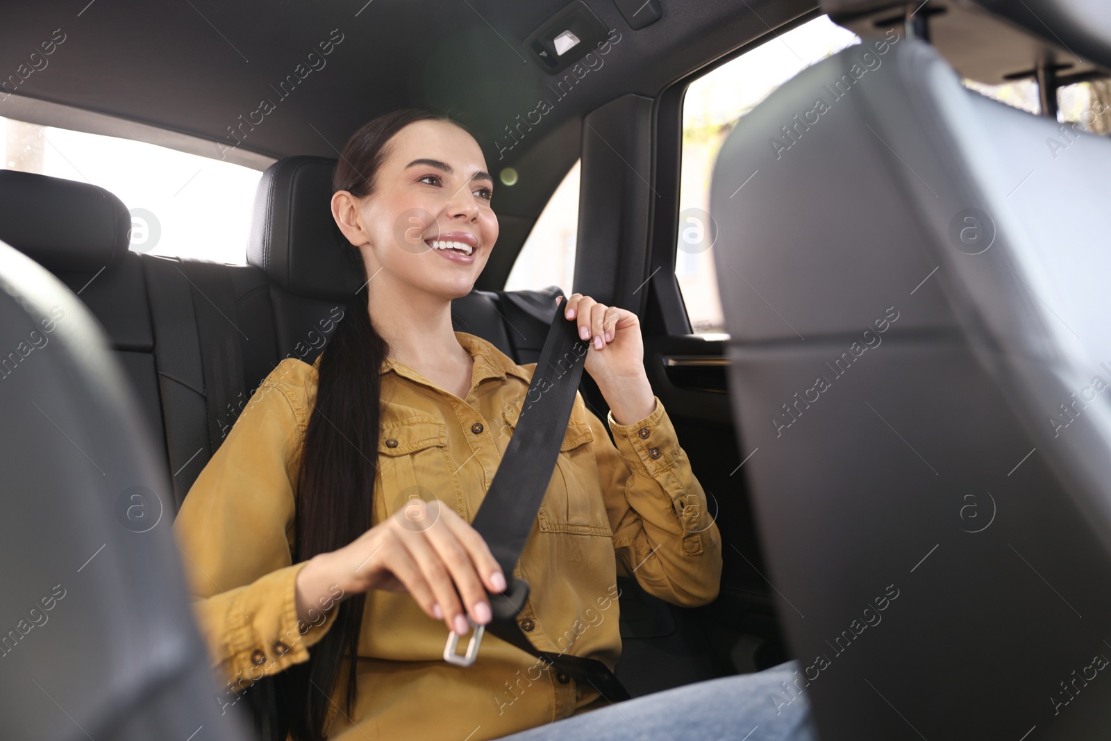 Photo of Woman fastening safety seat belt inside modern car