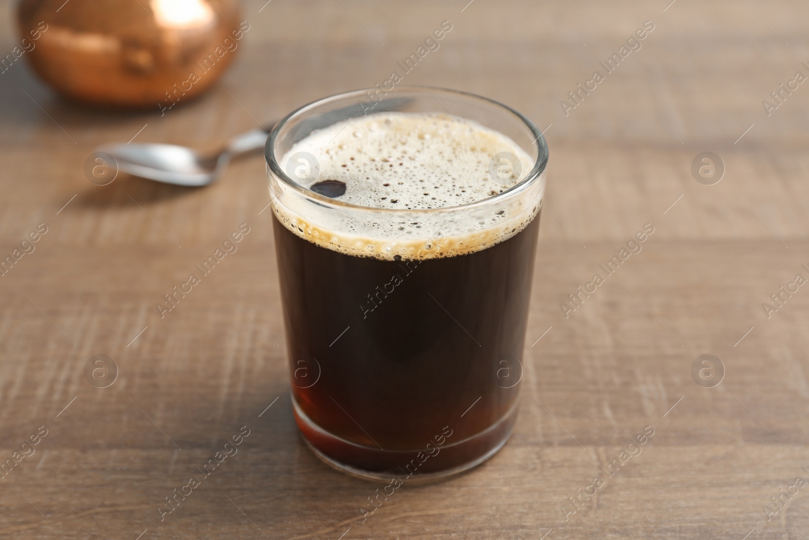 Photo of Glass of aromatic hot coffee on wooden table