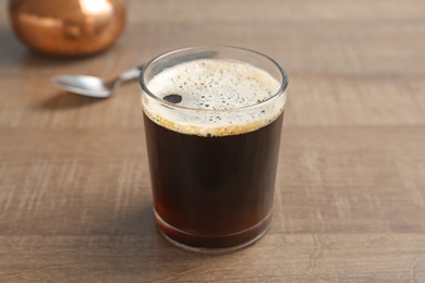 Photo of Glass of aromatic hot coffee on wooden table