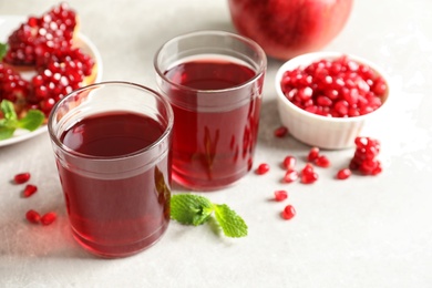 Composition with glasses of fresh pomegranate juice on table. Space for text