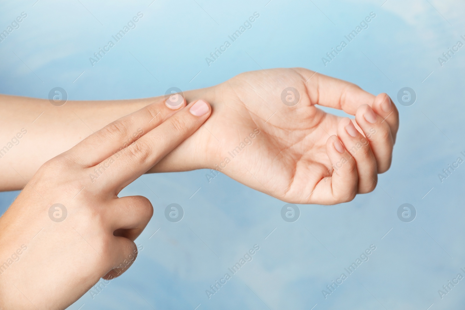 Photo of Woman checking pulse on wrist against color background, closeup