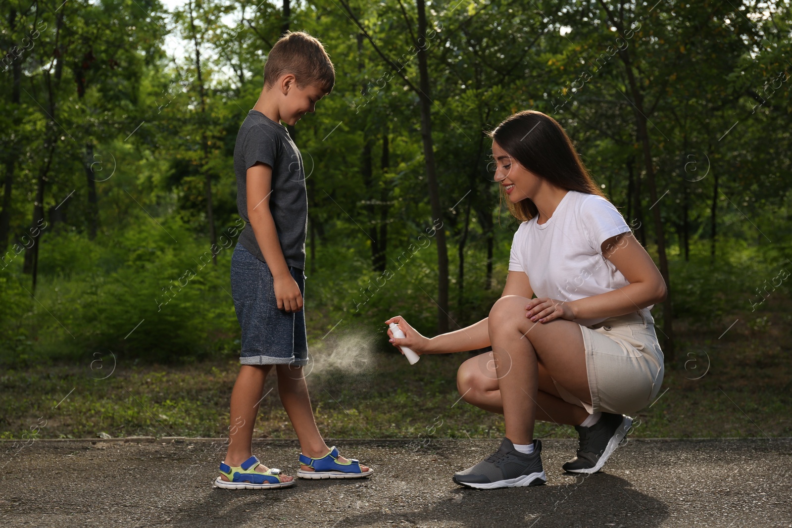 Photo of Woman applying insect repellent on her son's leg in park. Tick bites prevention