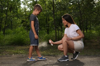 Woman applying insect repellent on her son's leg in park. Tick bites prevention