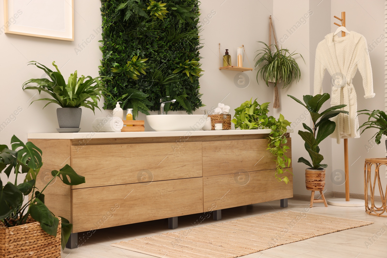 Photo of Green artificial plants, vanity and different personal care products in bathroom