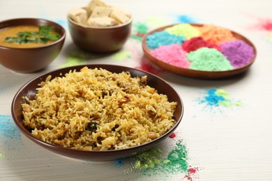 Photo of Traditional Indian food and color powders on white wooden table. Holi festival celebration