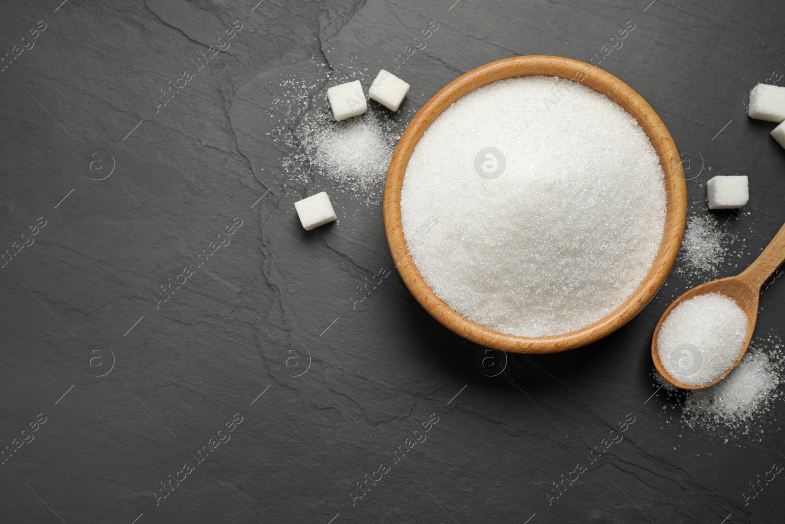 Photo of Flat lay composition with granulated sugar on dark table. Space for text