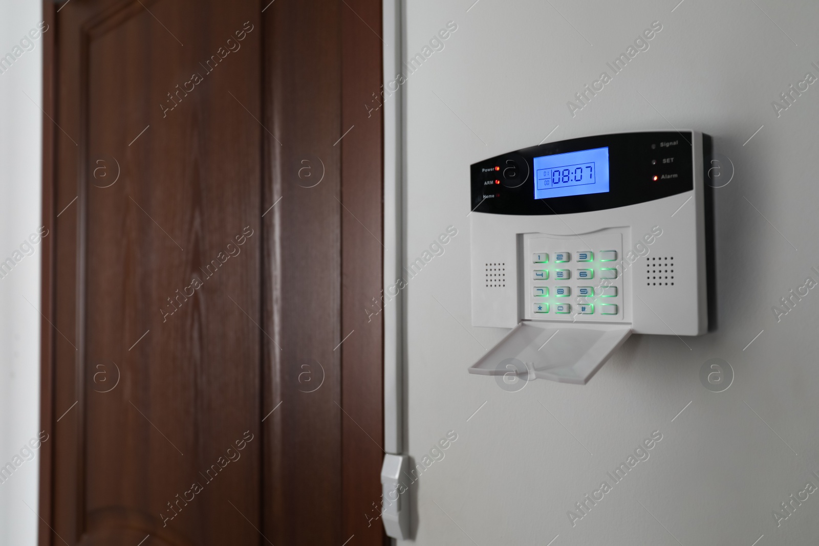 Photo of Home security alarm system on white wall near door, space for text