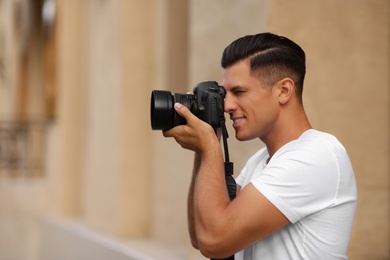 Photographer taking picture with professional camera on city street