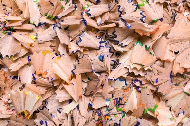 Photo of Pile of colorful pencil shavings as background, top view