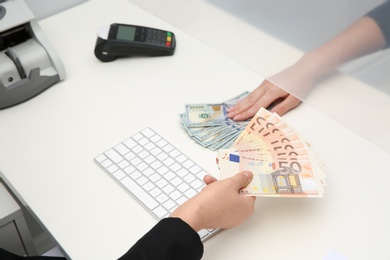 Woman exchanging money at cash department window, closeup