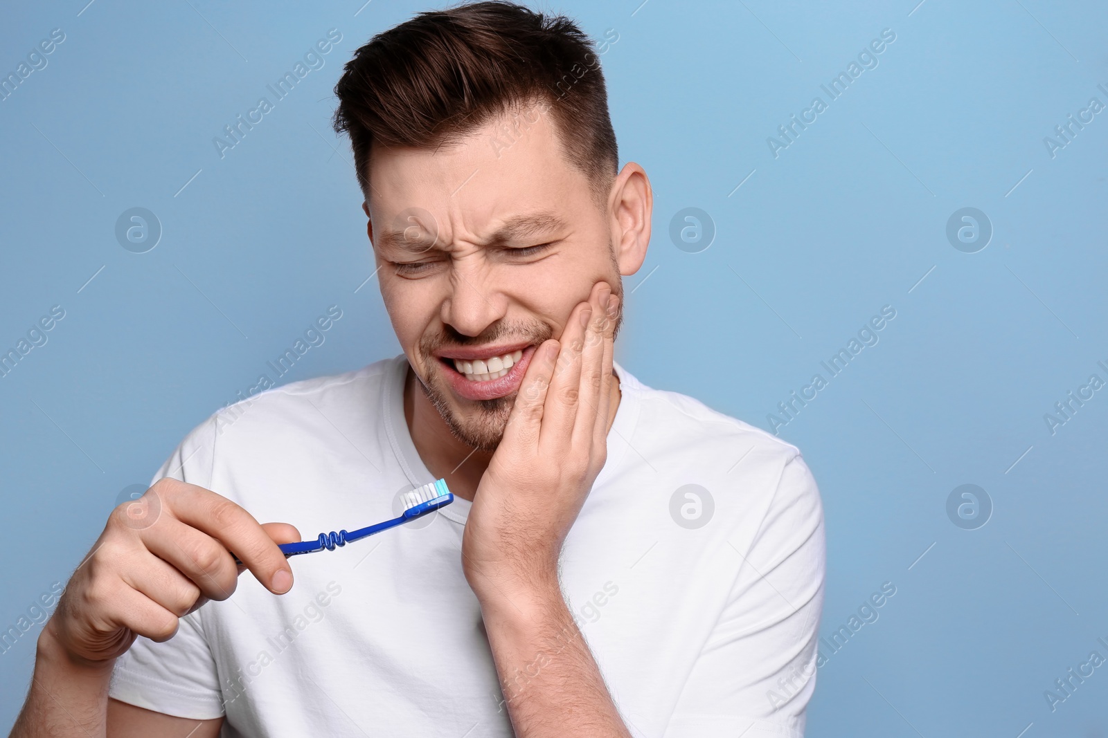 Photo of Young man suffering from toothache on grey background