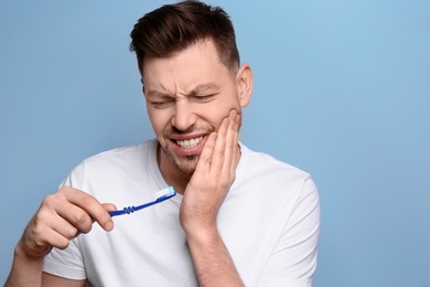 Young man suffering from toothache on grey background