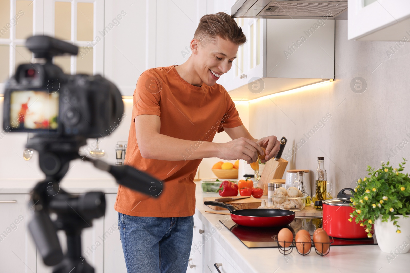 Photo of Smiling food blogger cooking while recording video in kitchen