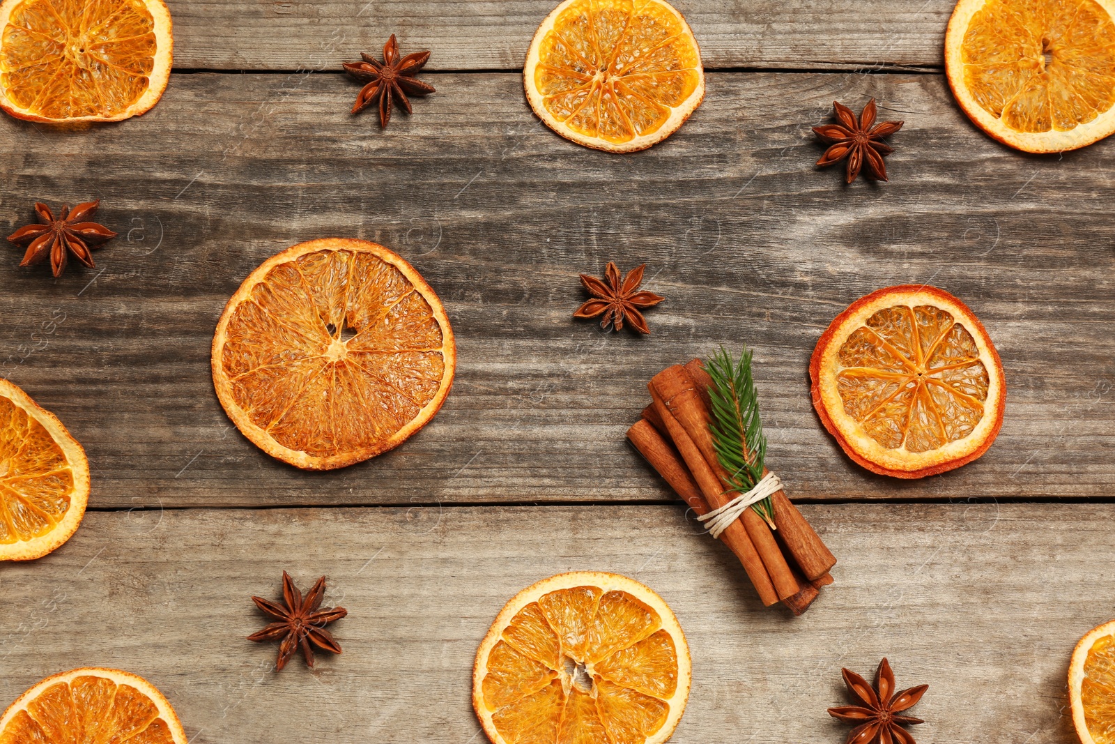 Photo of Flat lay composition with dry orange slices, anise stars and cinnamon sticks on wooden table