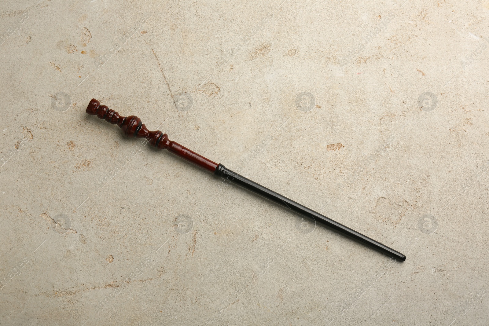 Photo of One magic wand on light textured background, top view