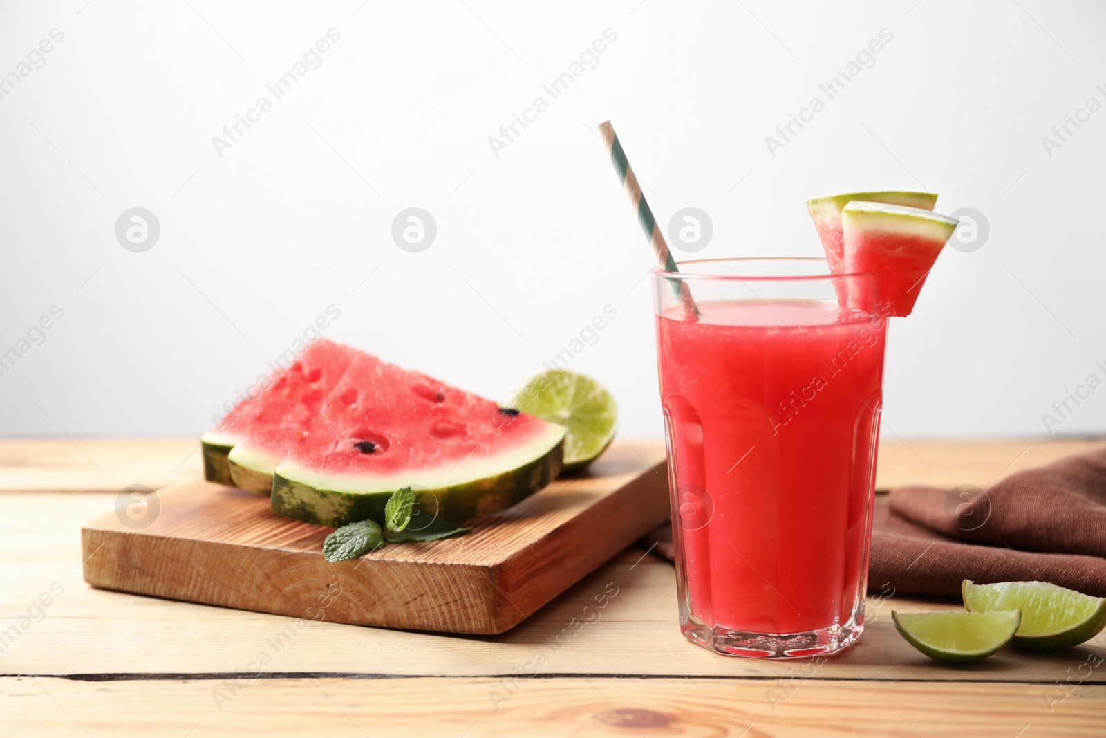 Photo of Summer watermelon drink in glass and sliced fruits on table