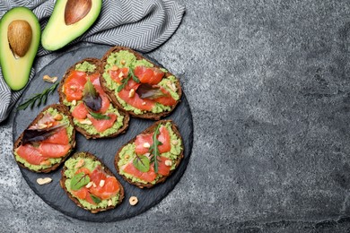 Photo of Delicious sandwiches with salmon, avocado and herbs on grey table, flat lay. Space for text