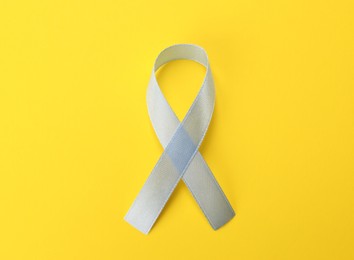 Photo of International Psoriasis Day. Ribbon as symbol of support on yellow background, top view