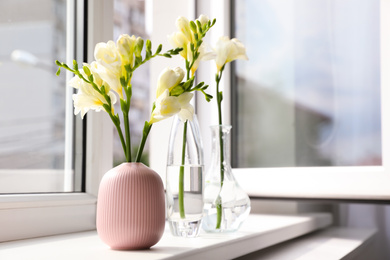 Beautiful white spring freesia flowers on window sill in room