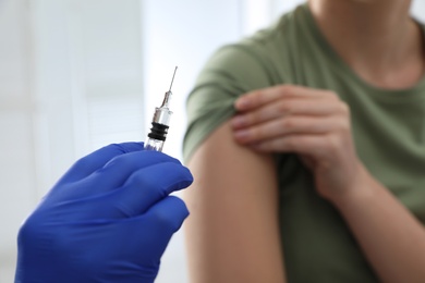 Doctor giving injection to woman in hospital, closeup. Immunization concept