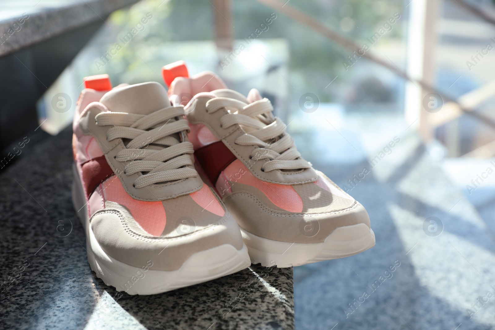 Photo of Pair of stylish women's sneakers on grey marble stairs indoors