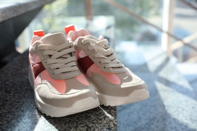 Photo of Pair of stylish women's sneakers on grey marble stairs indoors